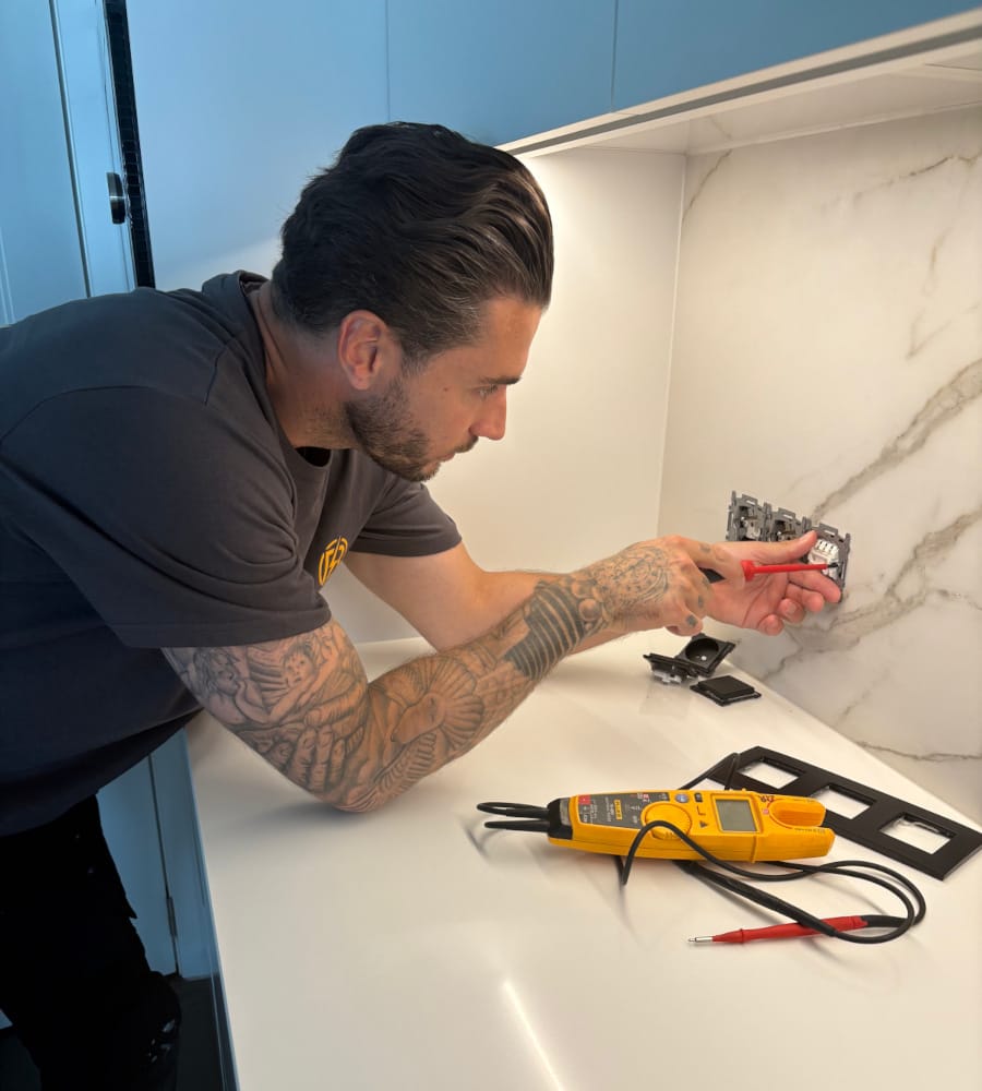 Elektricien Bouilliart demonstreert zijn vakmanschap bij de installatie van een stopcontact in een moderne keuken.